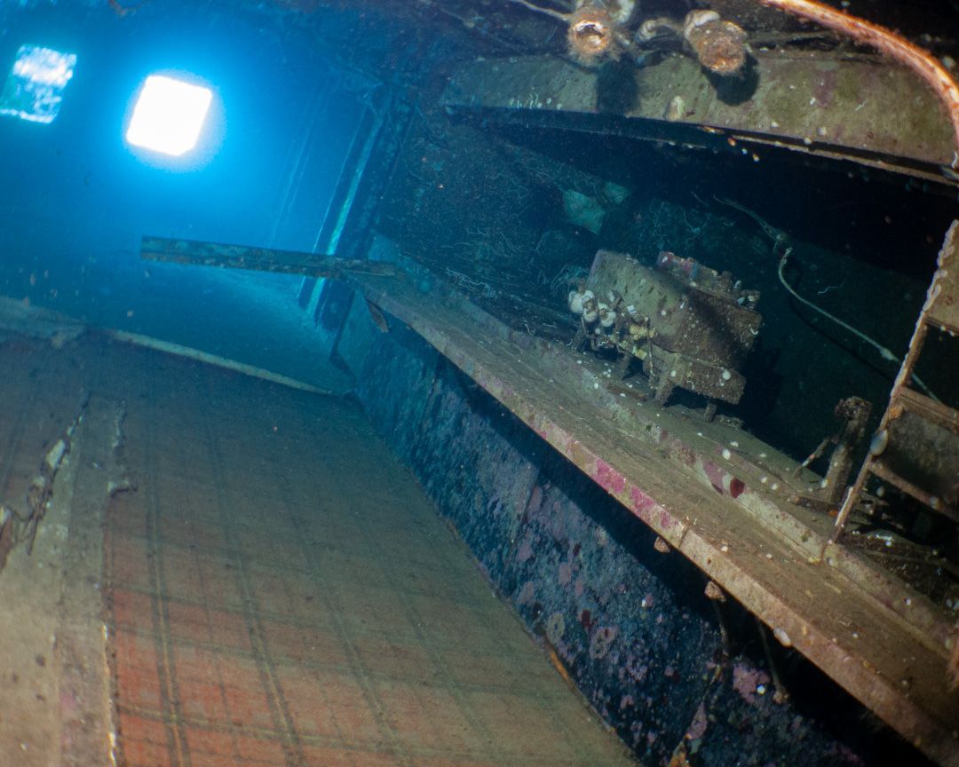 A very old tank is underwater with a blue light shining on it.