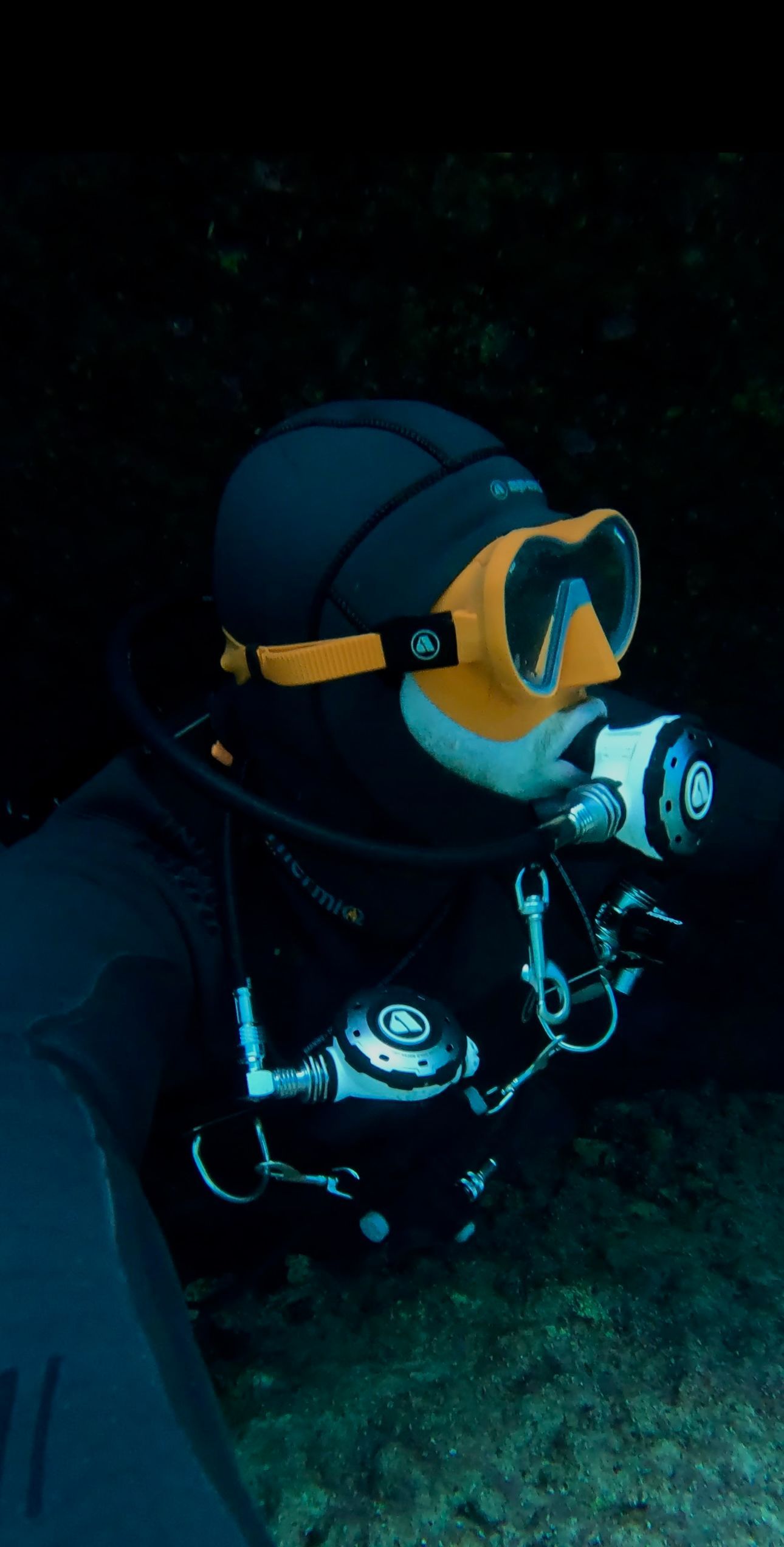 A man wearing a mask and goggles is swimming in the water.