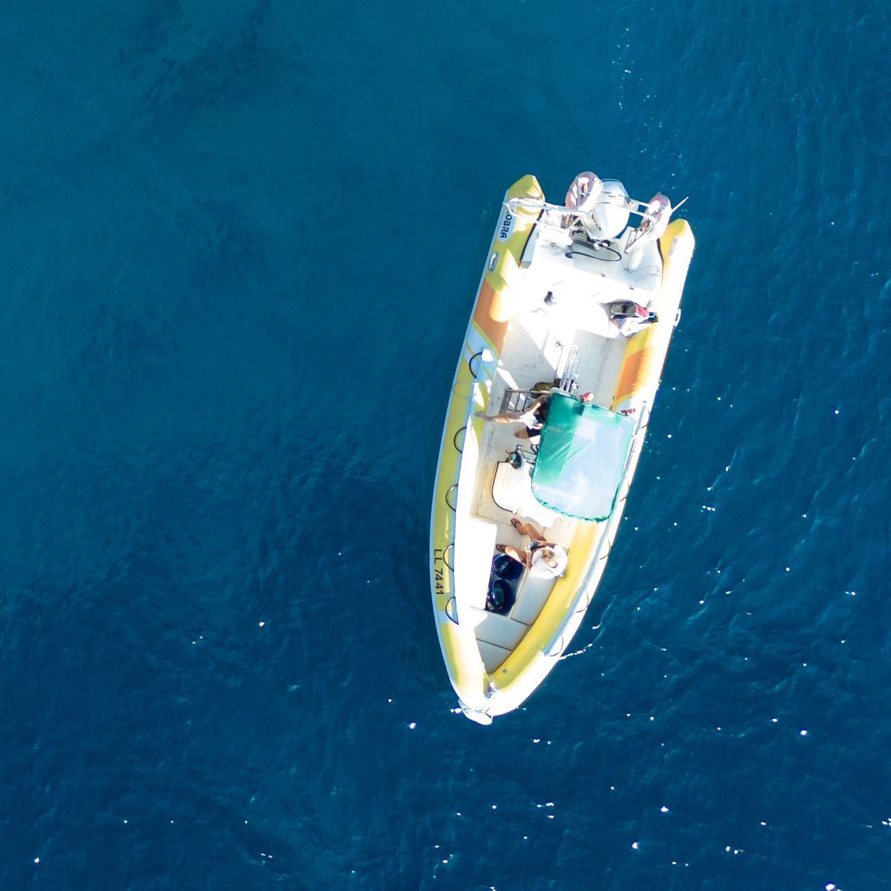 An aerial view of a yellow and white boat in the ocean