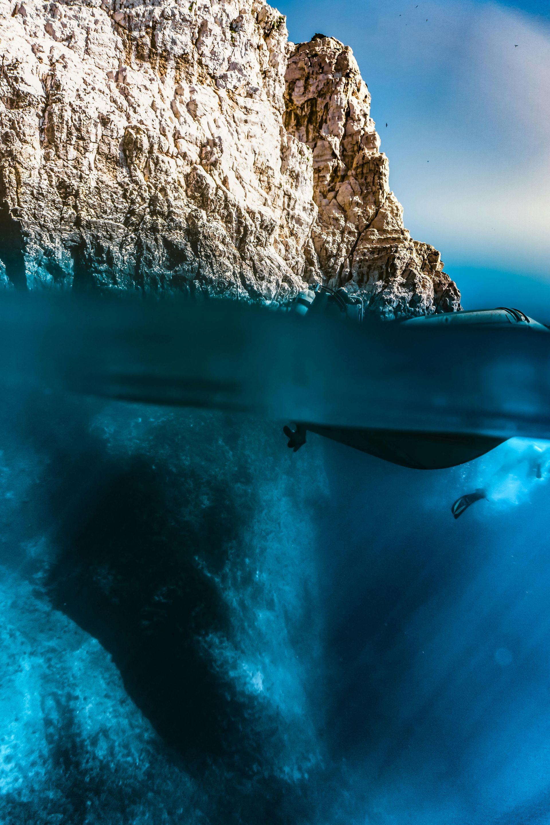 A whale is swimming in the ocean near a rocky island