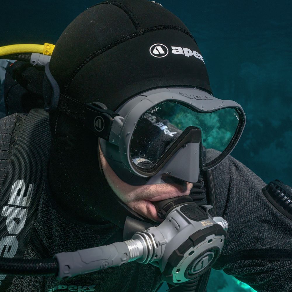 A scuba diver wearing a black cap with the word apes on it