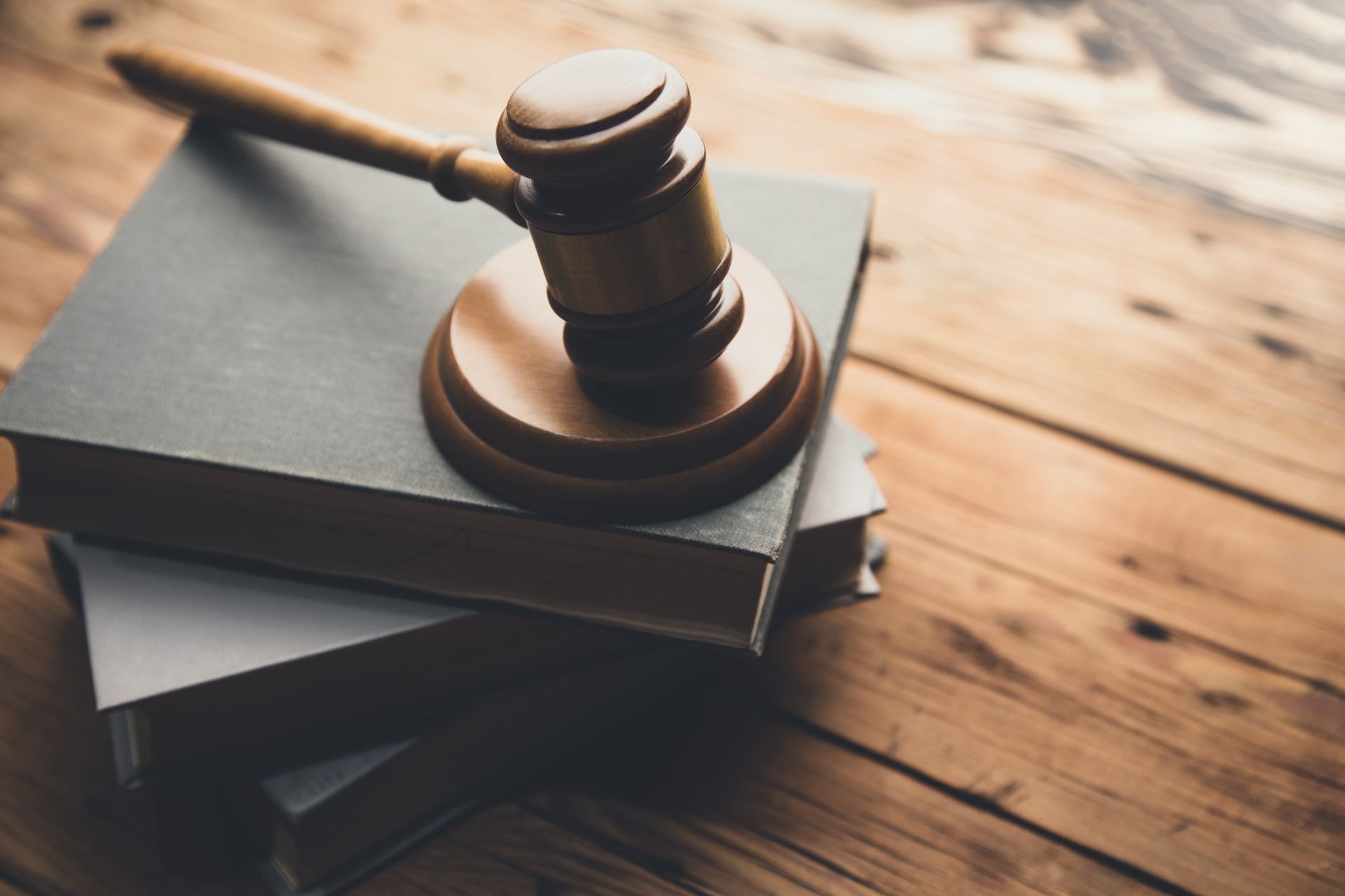 Wooden gavel on top of two stacked books on a wooden surface.