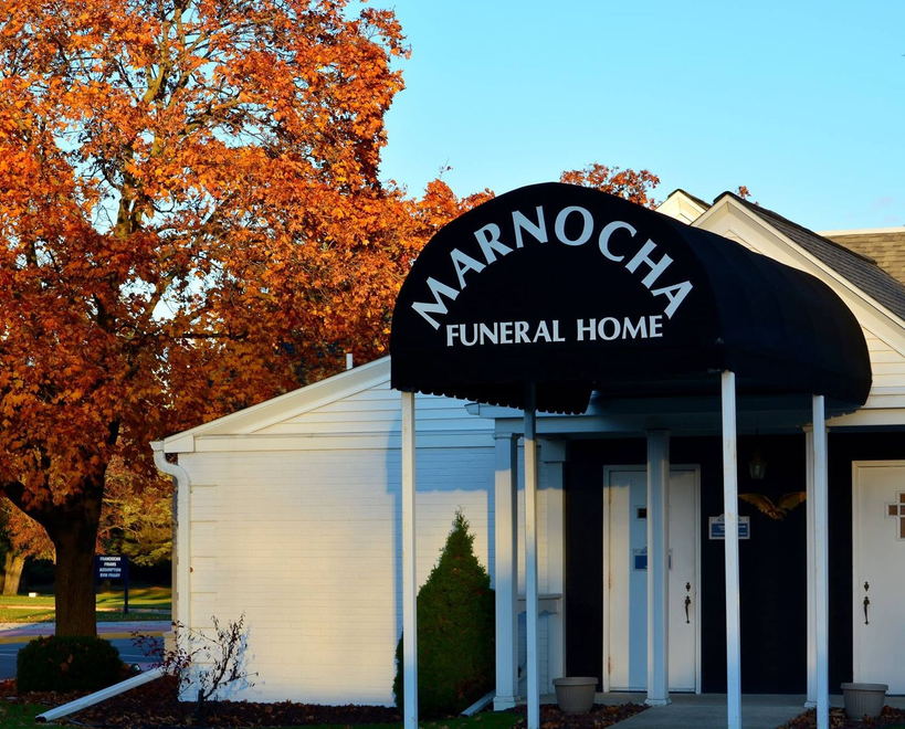 Marnoche Funeral Home entrance with black awning, white building, and orange autumn trees