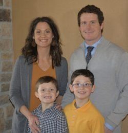 Two adults and two children posing indoors, smiling at the camera.