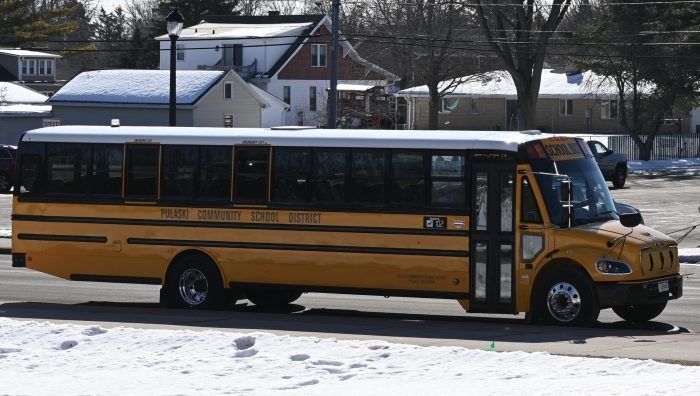 Yellow school bus parked in a snowy neighborhood street with houses in the background
