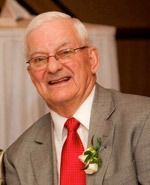 Smiling man in a gray suit with a red tie and white boutonniere