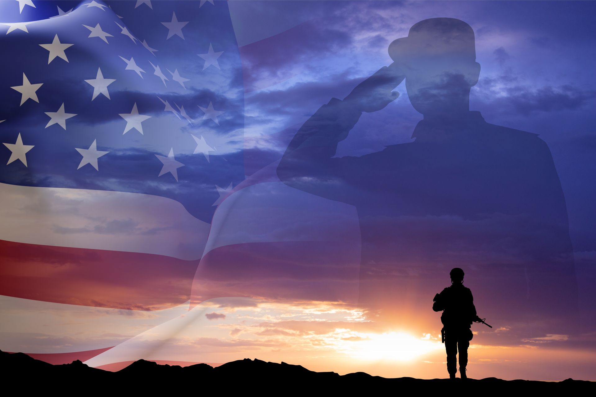 Silhouetted soldier at sunset with U.S. flag and faint saluting figures in the sky
