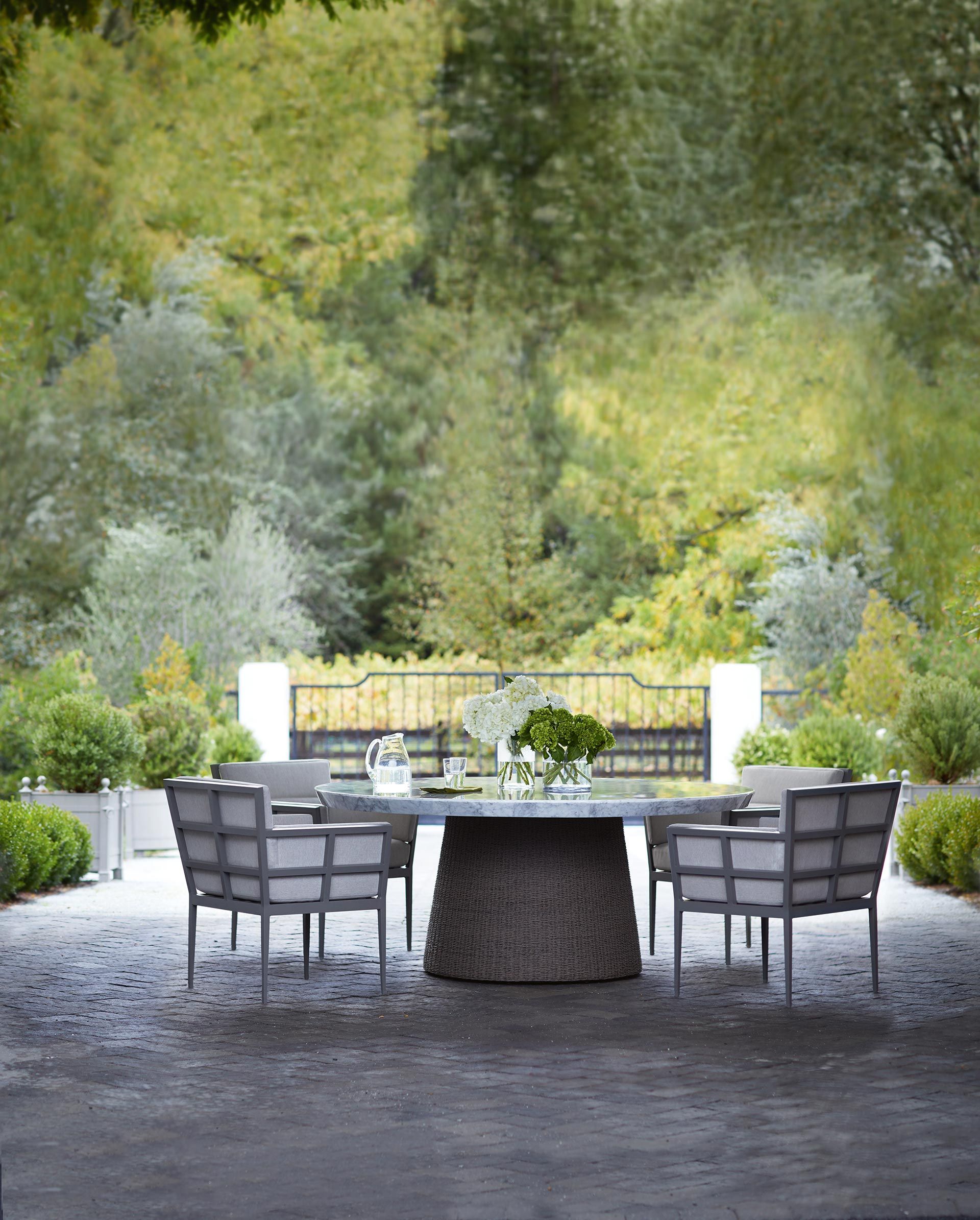 a table and chairs outside with trees in the background