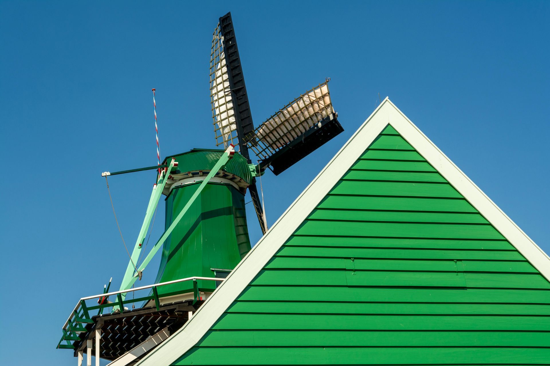A green windmill is on top of a green building