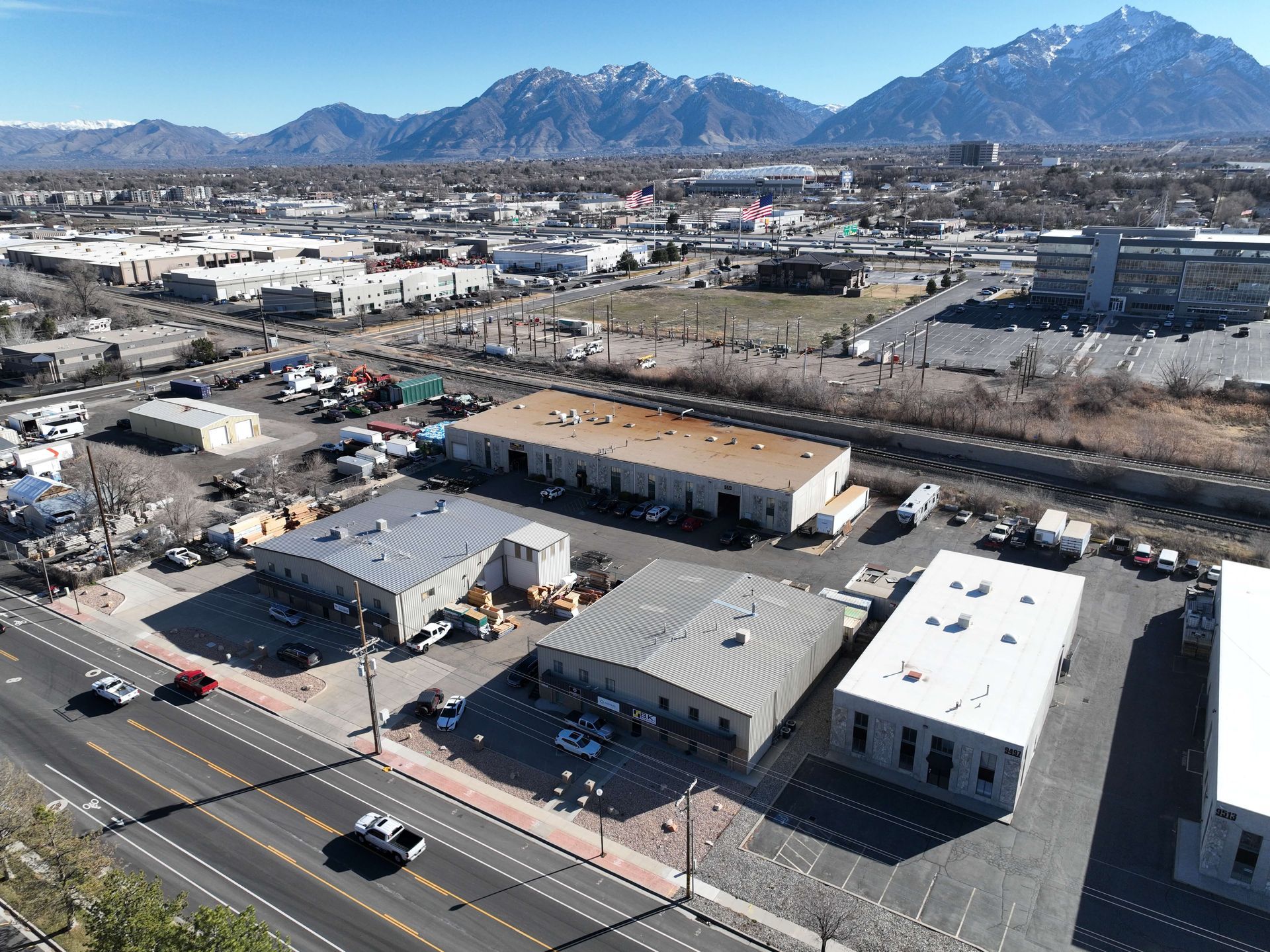 Aerial view of industrial buildings with mountains in the background and a street in the foreground.