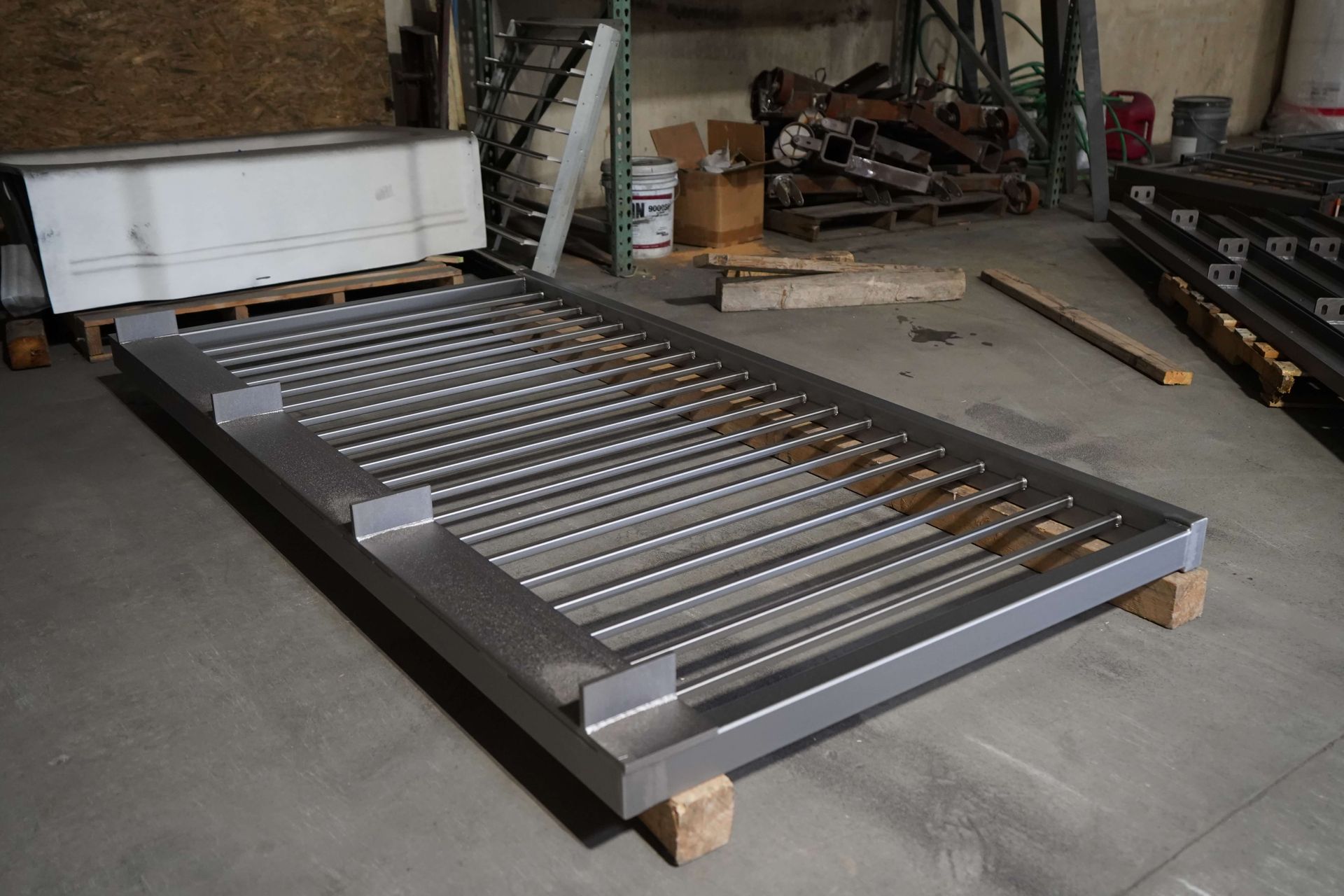 A metal grate is sitting on a wooden pallet in a warehouse.