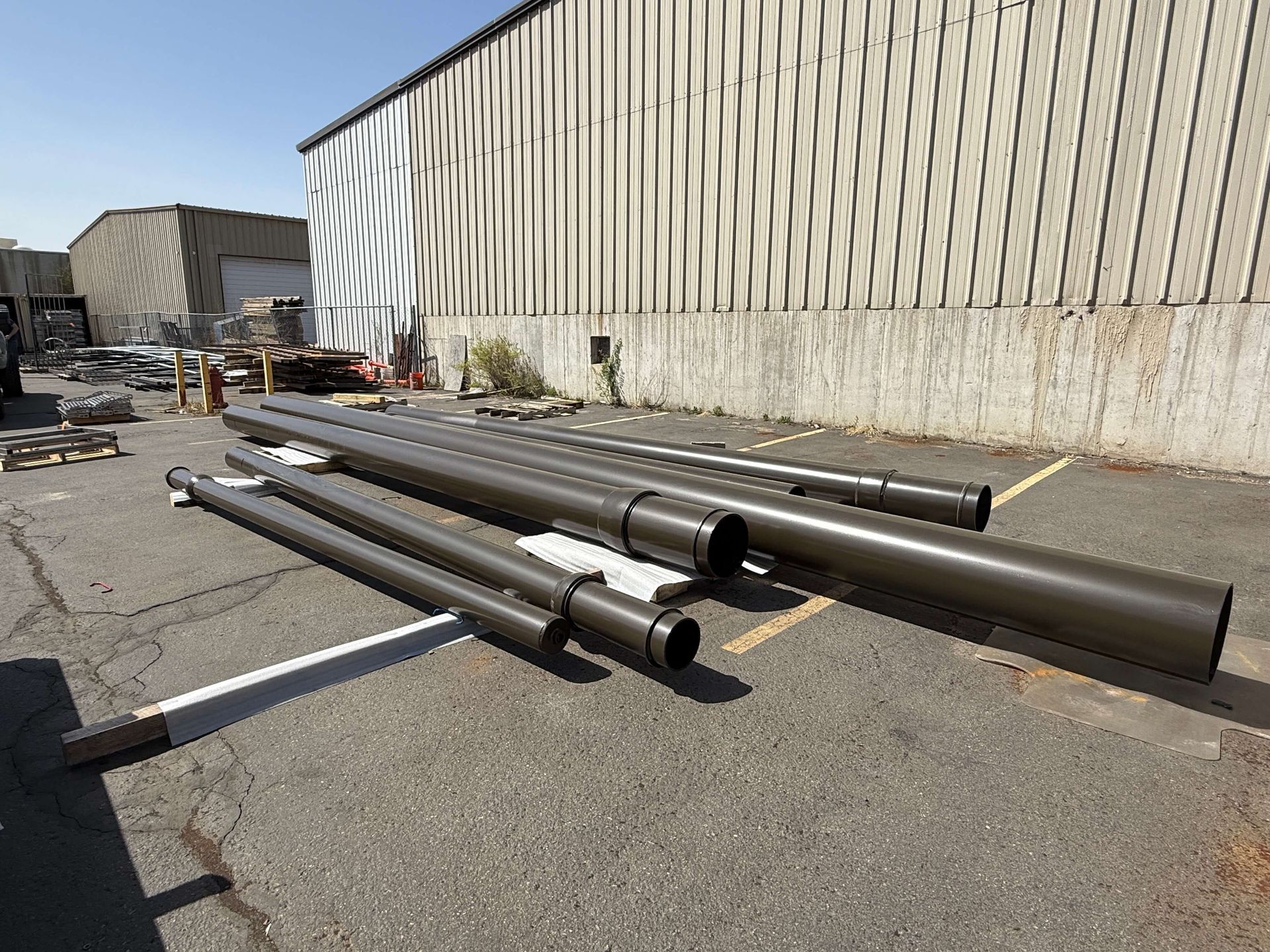 A bunch of powder coated pipes are laying on the ground in front of a building
