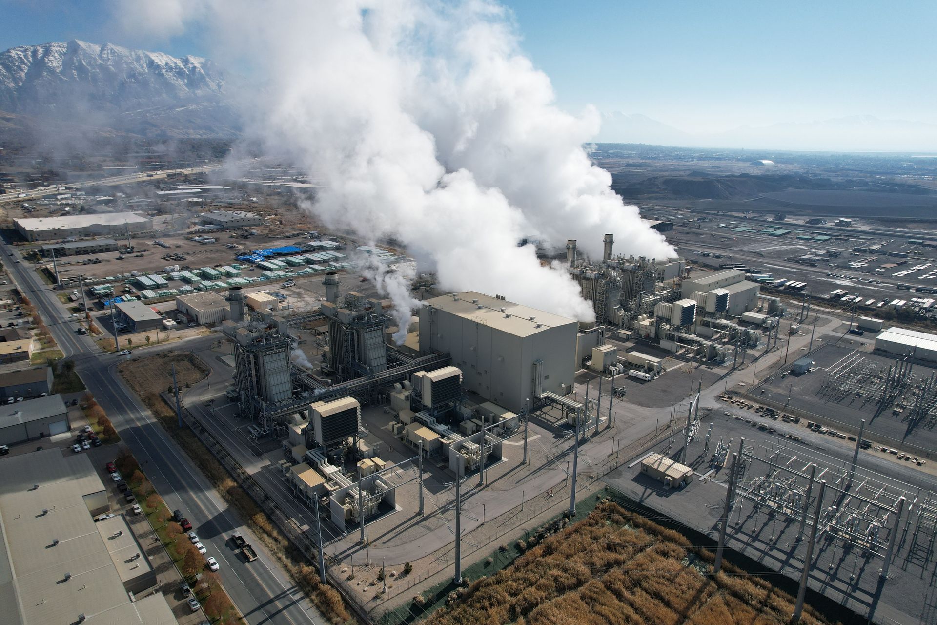 Aerial view of an industrial power plant with thick white steam rising from large smokestacks