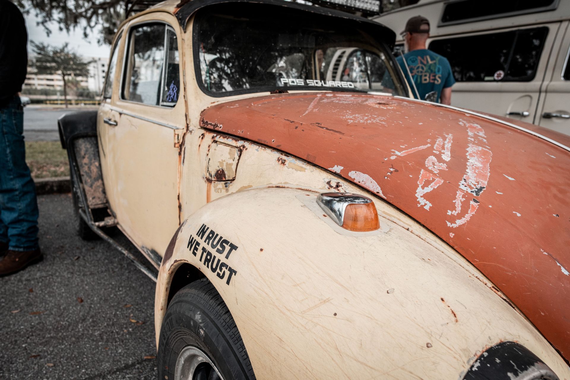 Rusty cream and orange vintage pickup truck at an outdoor car show, with weathered paint and rust patches
