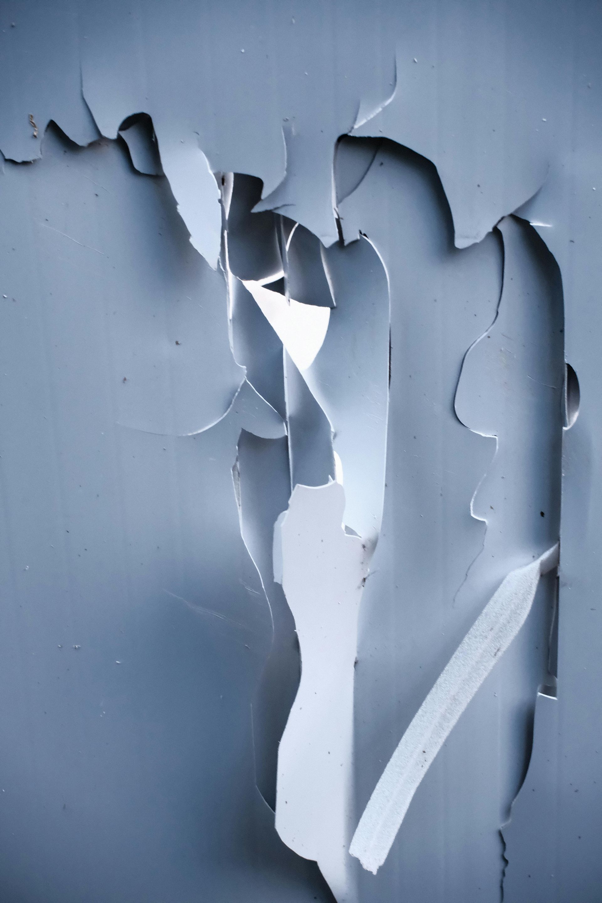 Peeling blue paint revealing white layers underneath