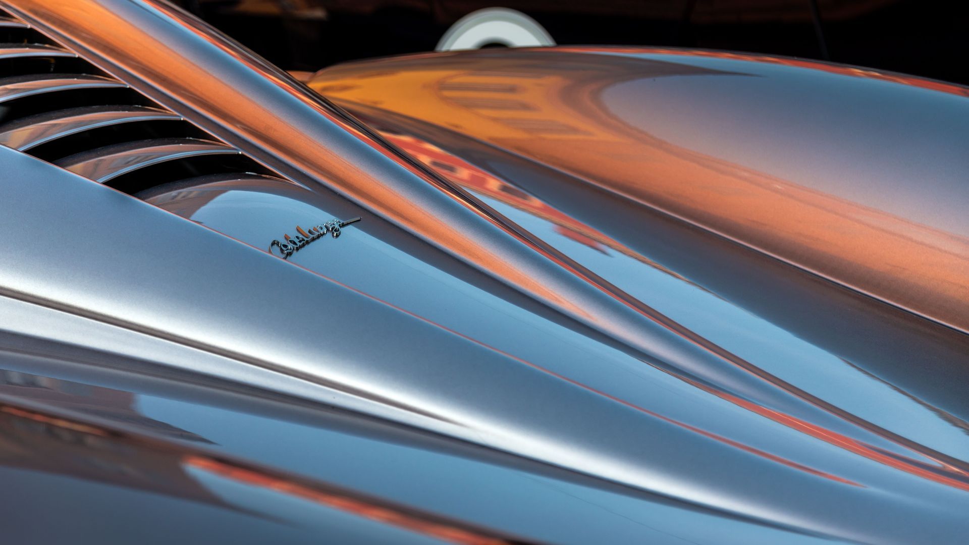 Close-up of a sleek silver and orange sports car hood with aerodynamic curves