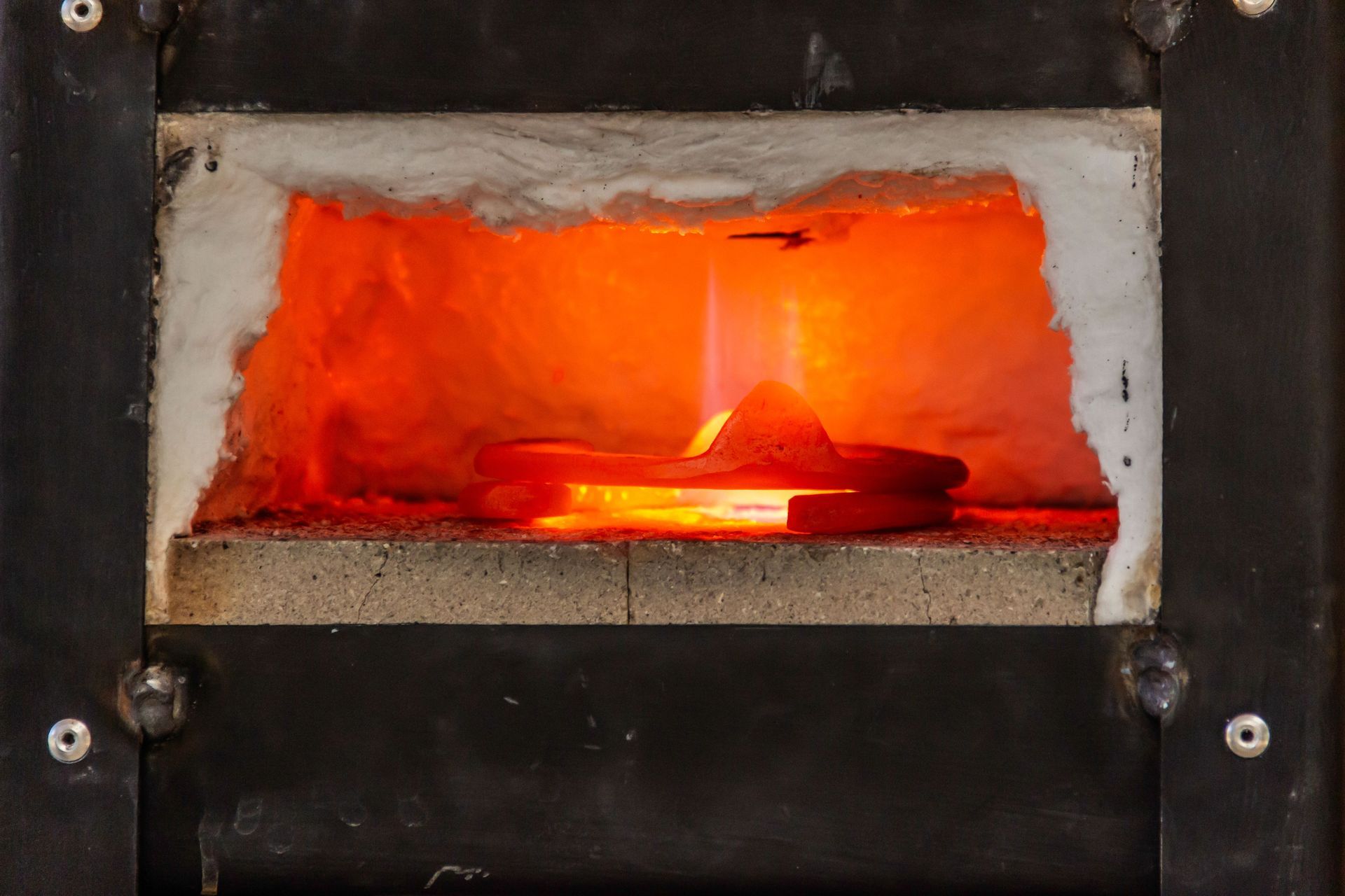 Glowing orange fire inside a rectangular brick furnace opening
