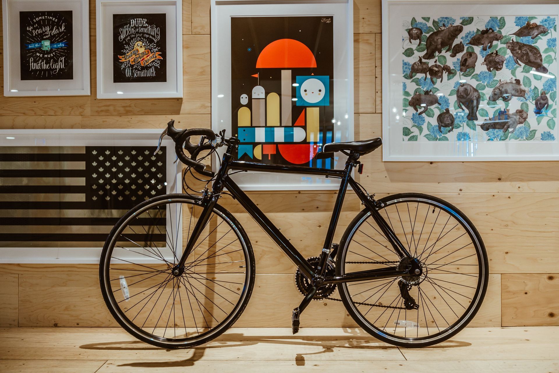 Adult black road bicycle displayed against a wood-paneled wall
