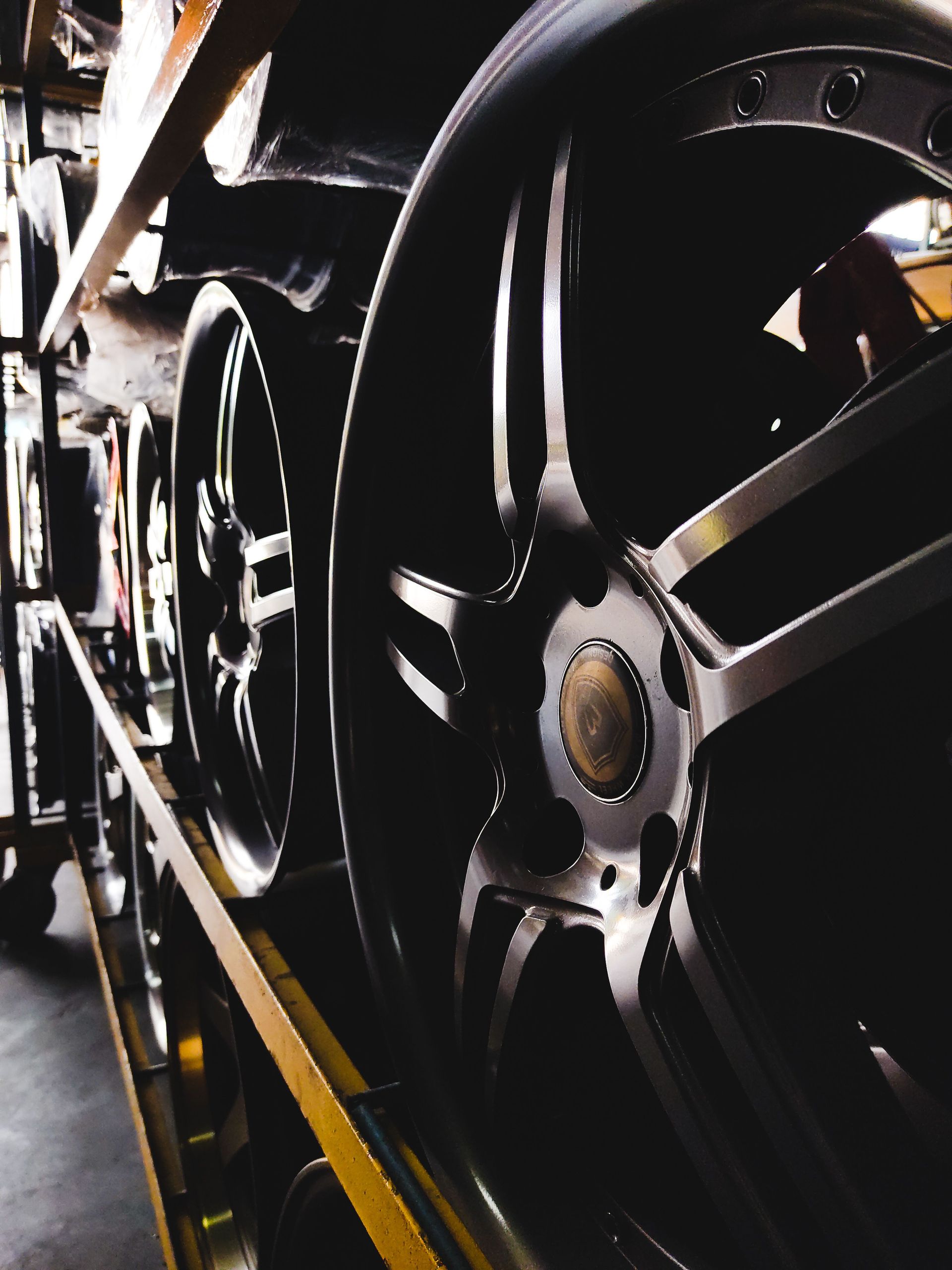 Close-up of a black steam locomotive wheel and metal rods on railroad tracks