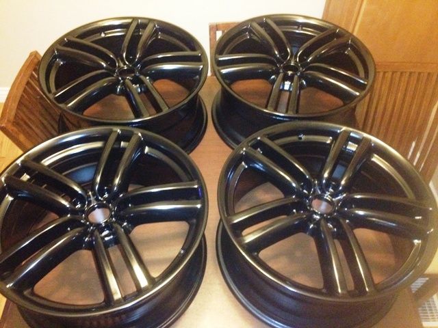 Four black wheels are sitting on a wooden table