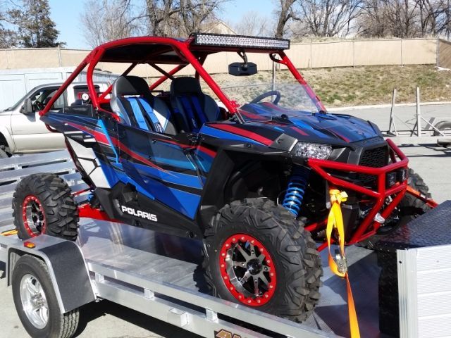 A blue and red atv is on a trailer