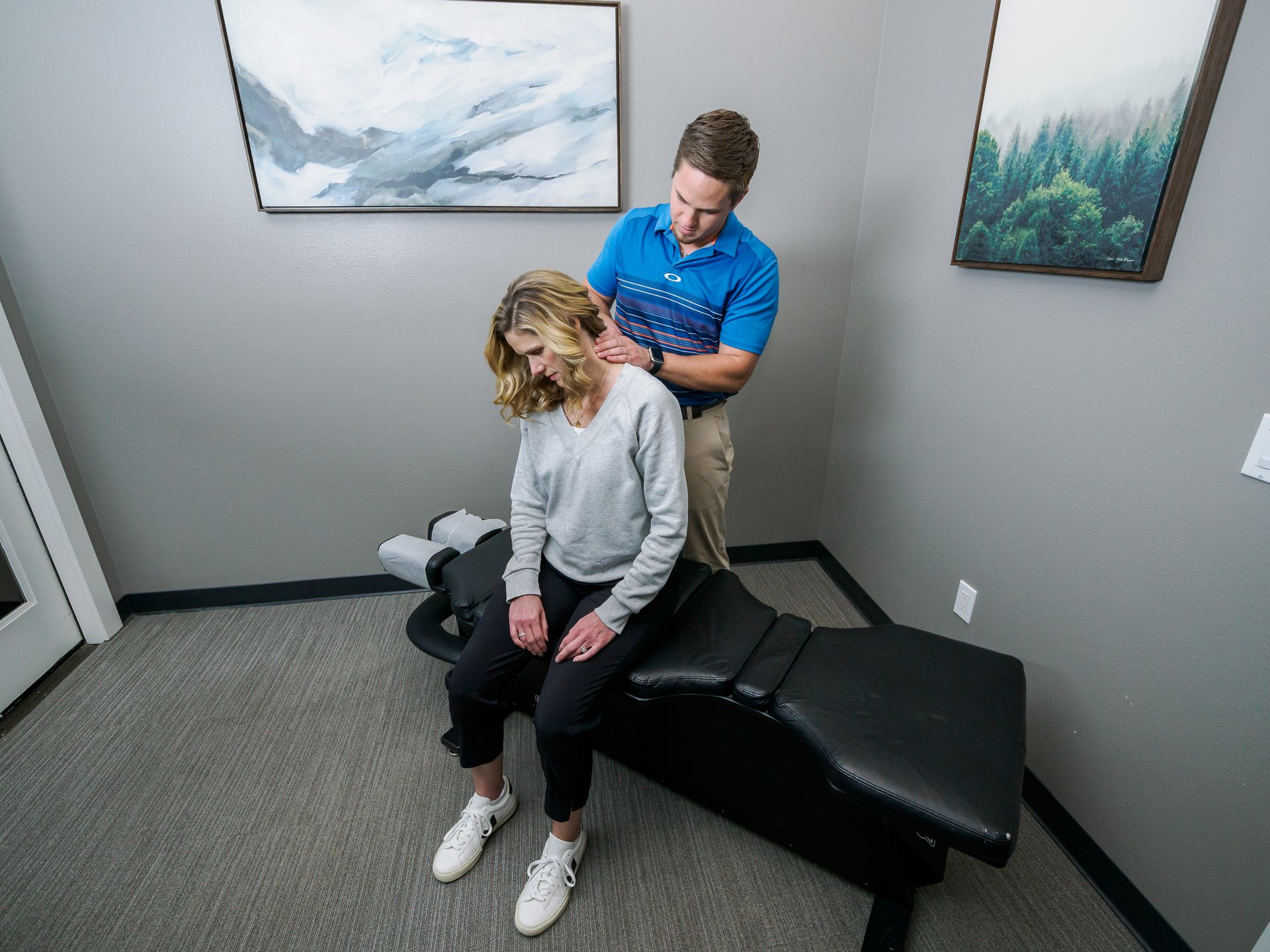 A man is examining a woman 's neck while she sits on a table.