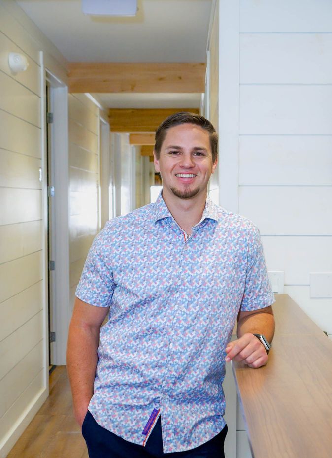 A man in a blue shirt is standing next to a counter in a hallway.