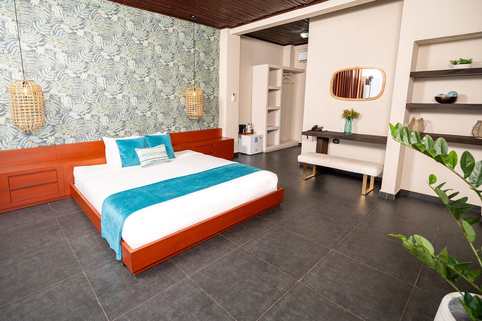 Modern bedroom with orange bed frame, teal accents, tiled floor, and vanity table beside a plant.