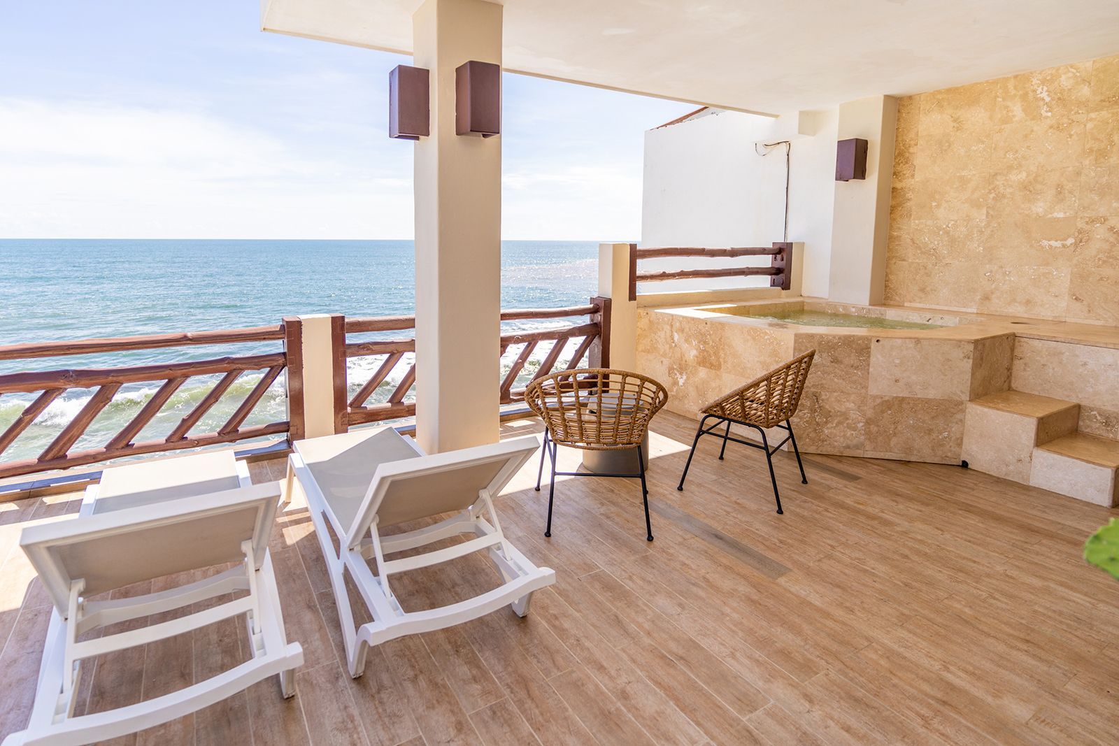 Beachfront patio with lounge chairs and small table overlooking the ocean