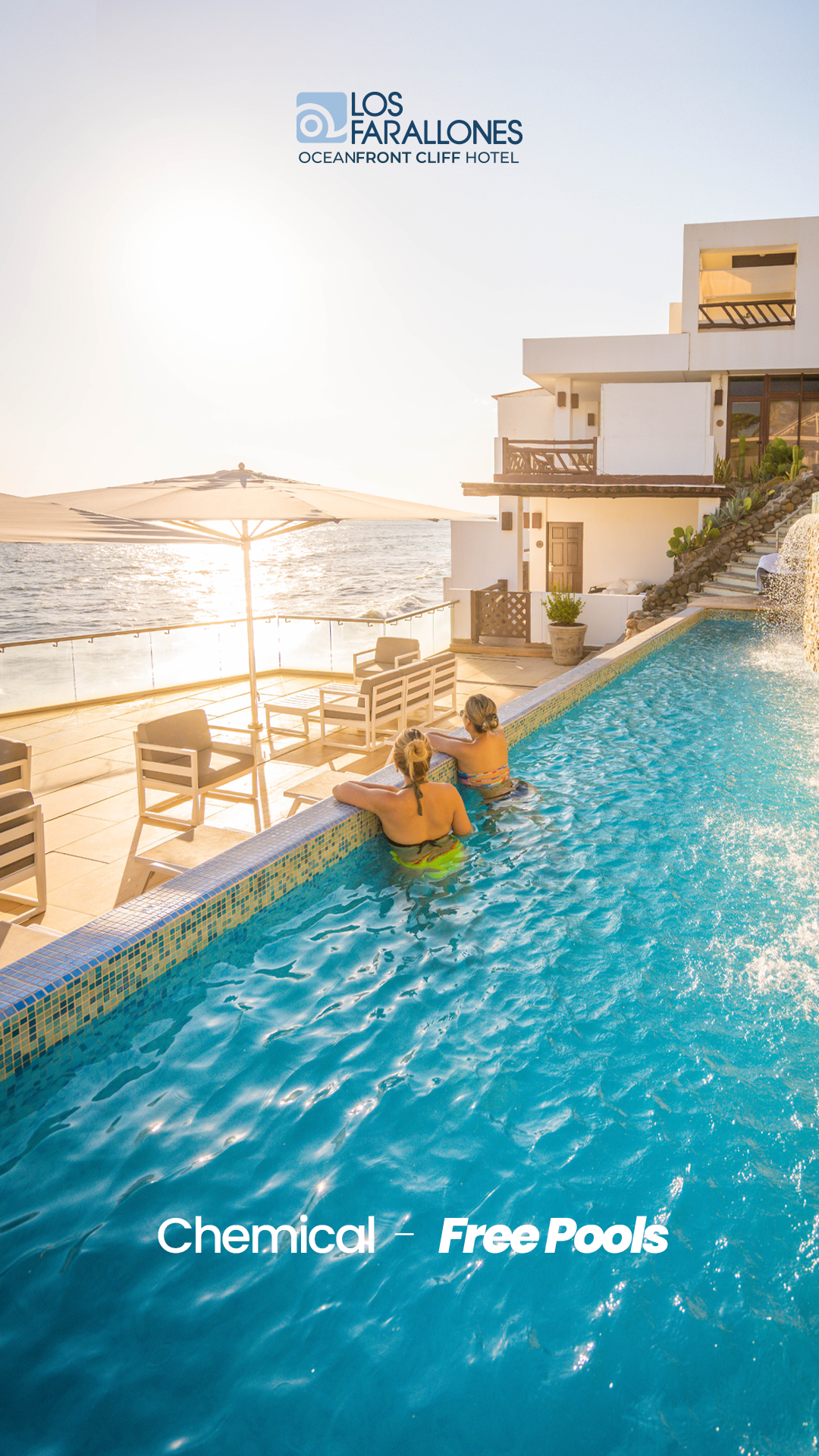 Infinity pool overlooking the sea at a luxury resort, with two people relaxing in the water at sunset.