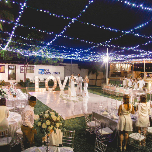An outdoor evening wedding reception featuring a large, illuminated