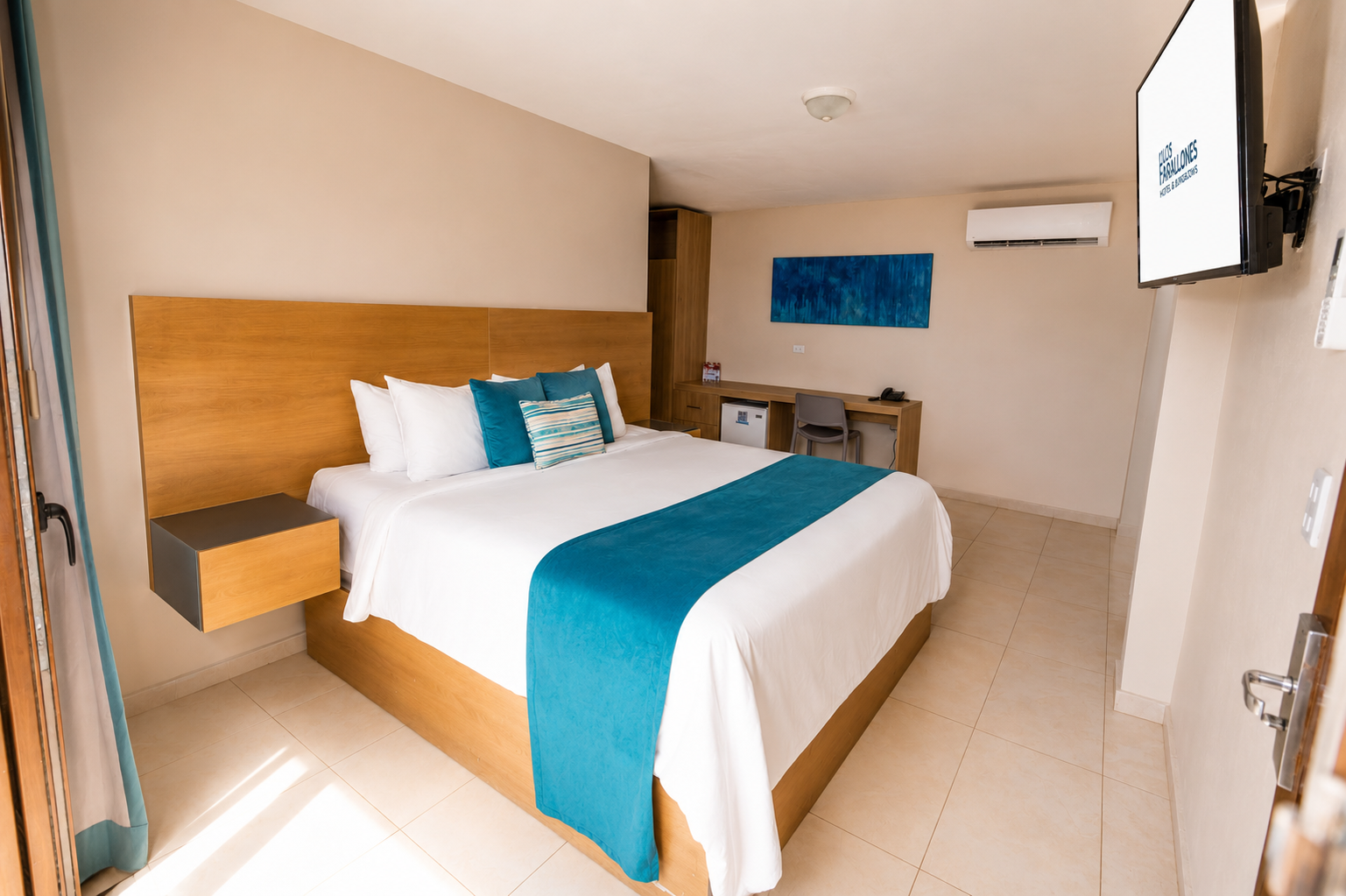 Modern hotel room with a double bed, teal accents, desk, and wall-mounted TV