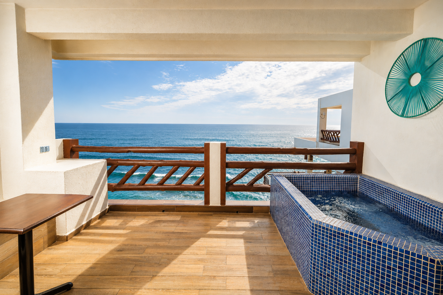Ocean-view balcony with wooden deck, lounge bed, and blue-tiled hot tub