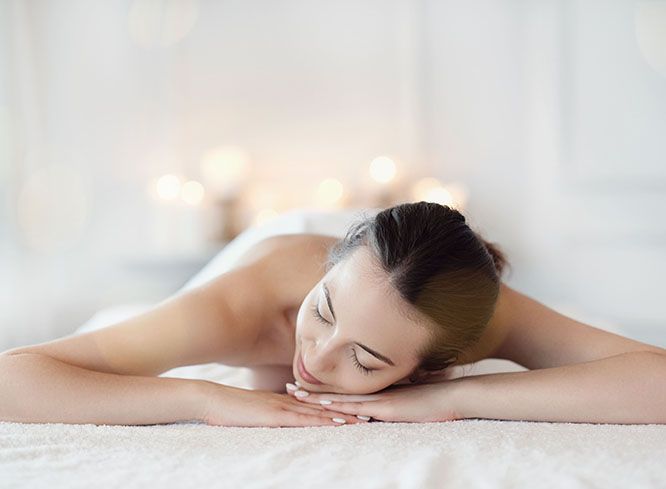 A person lying face down with eyes closed, resting their head on their hands during a spa treatment.