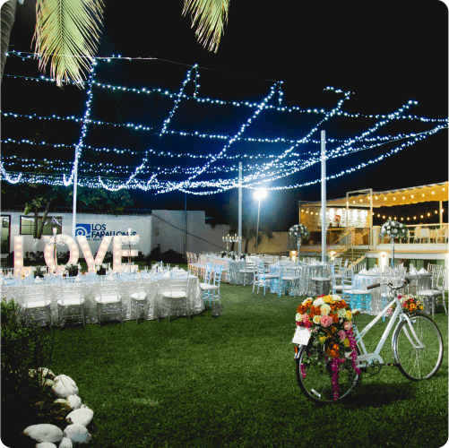 An outdoor night event with white tables, large illuminated