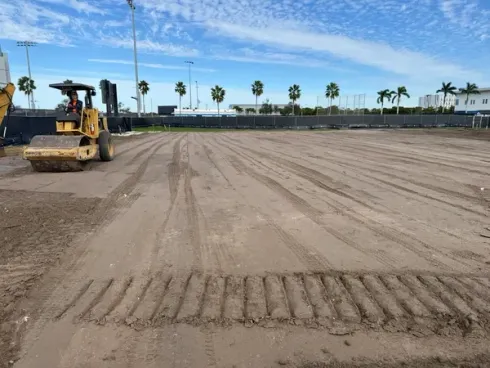 Smooth-drum roller compacting a large graded commercial pad