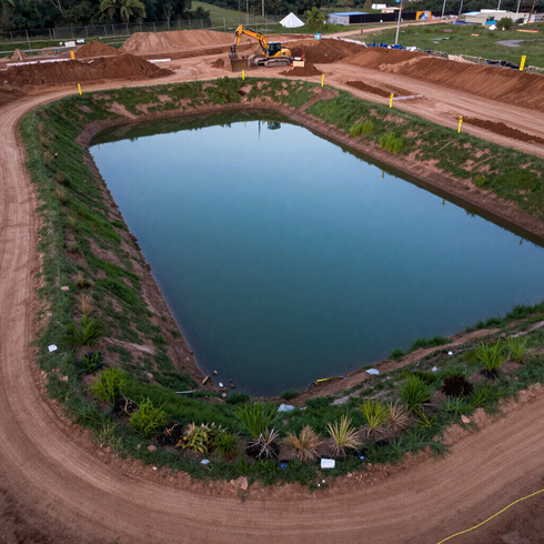 Newly excavated retention pond with shaped banks on a construction site