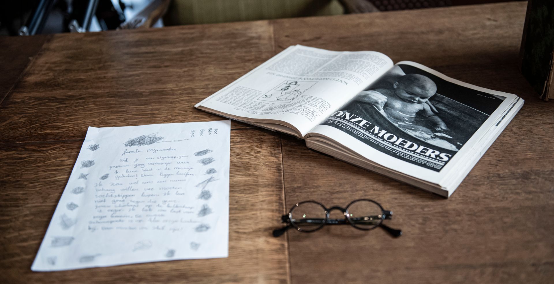 Op een houten tafel liggen een handgeschreven document, een boek met de titel