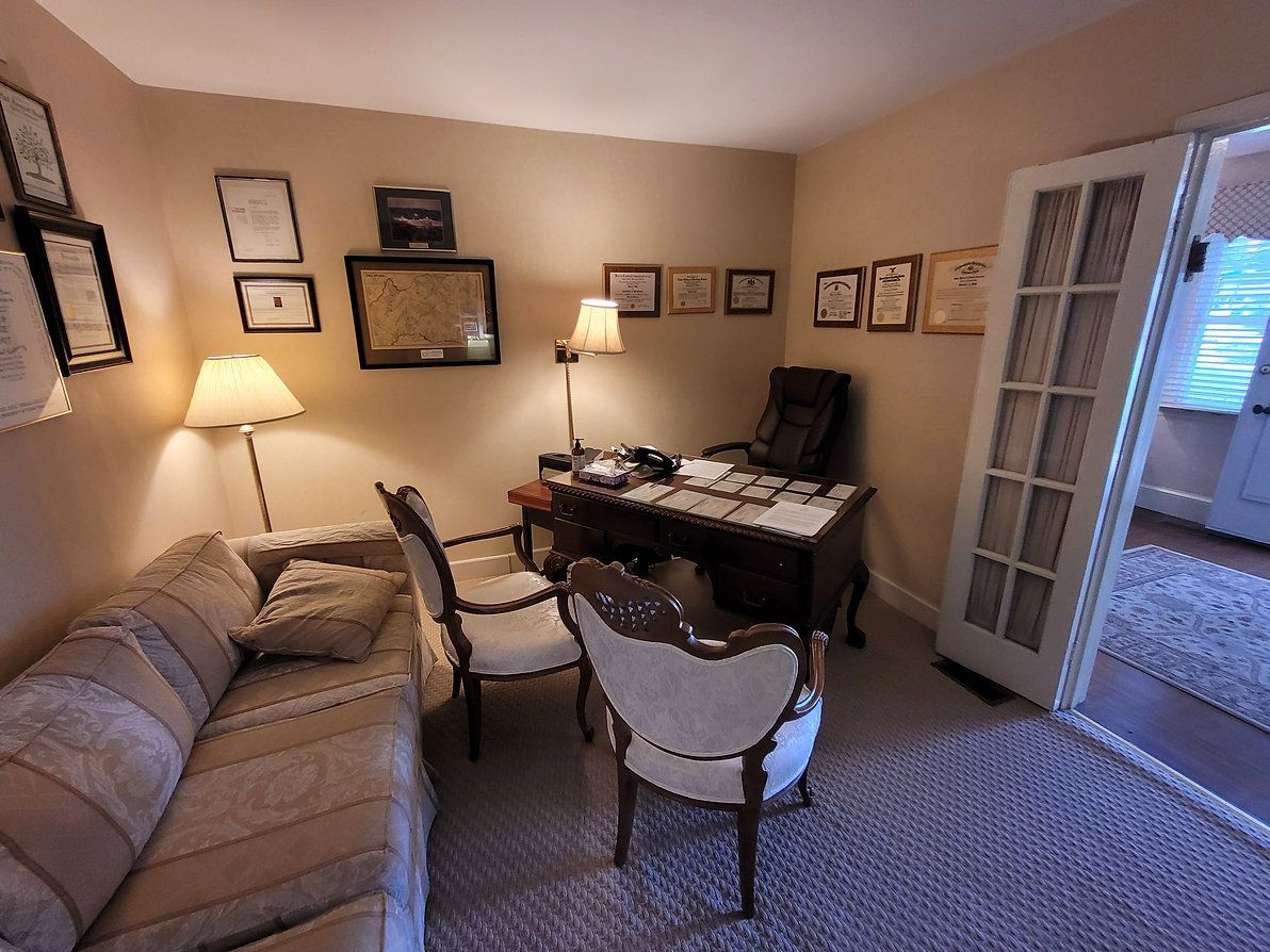 Cozy home office with desk, lamps, sofa, and two chairs in a beige room