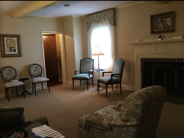 Cozy living room with armchairs, a window lamp, and a fireplace.