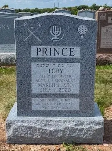 Gravestone with Star of David and globe symbols, engraved “PRINCE” and memorial text for Toby on a gray stone monument