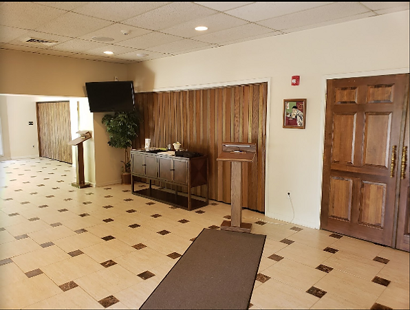 Hotel lobby with tiled floor, front desk, potted plant, and wooden doors
