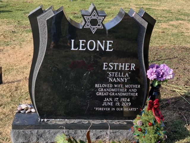 Black granite gravestone with Star of David and purple flowers in a cemetery