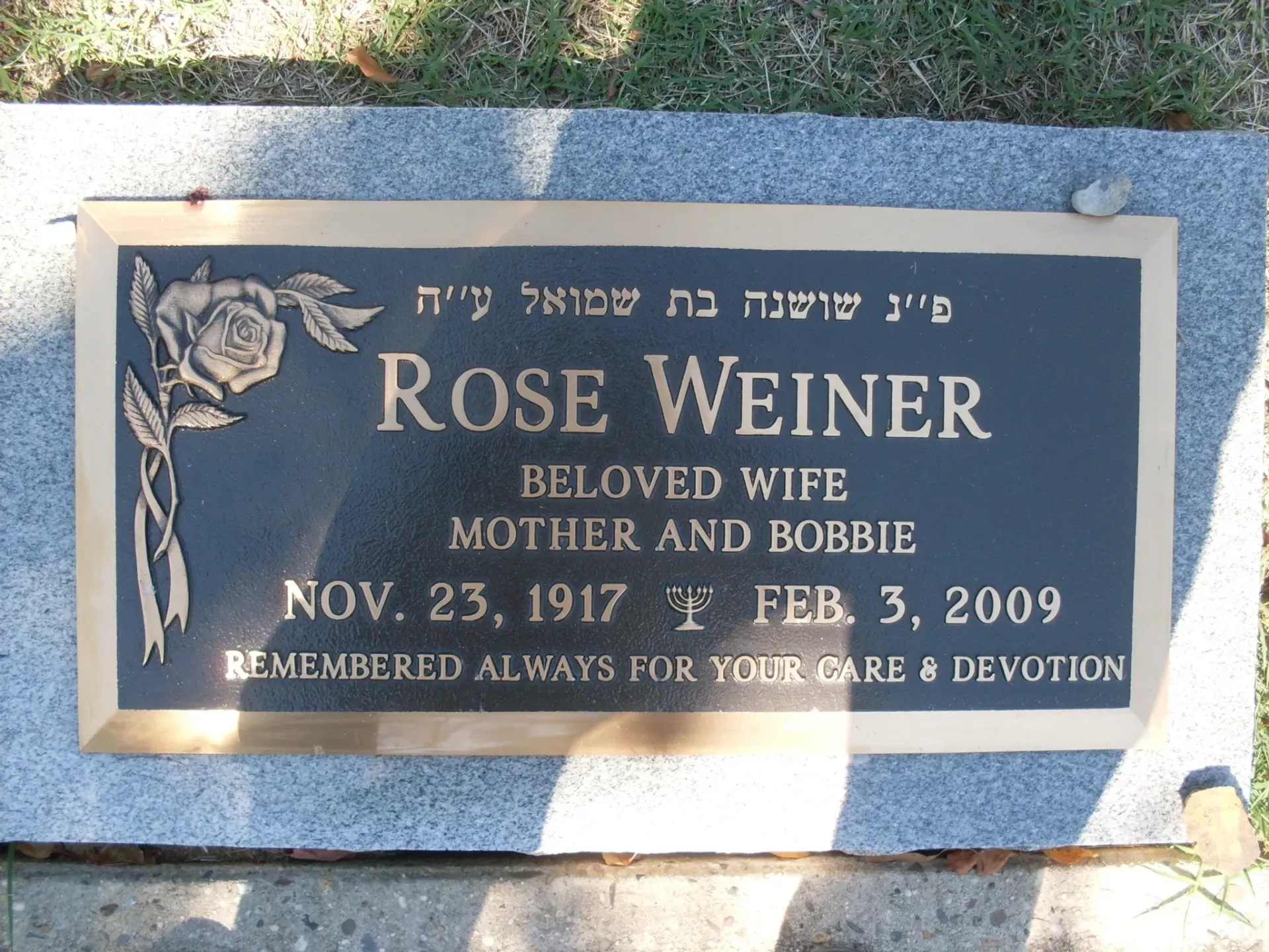 Gray memorial plaque with rose engraving for Rose Weiner in a stone setting