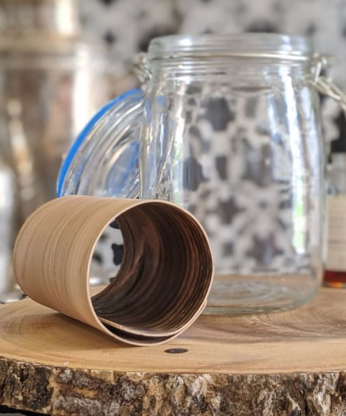 A jar and a roll of toilet paper on a wooden cutting board