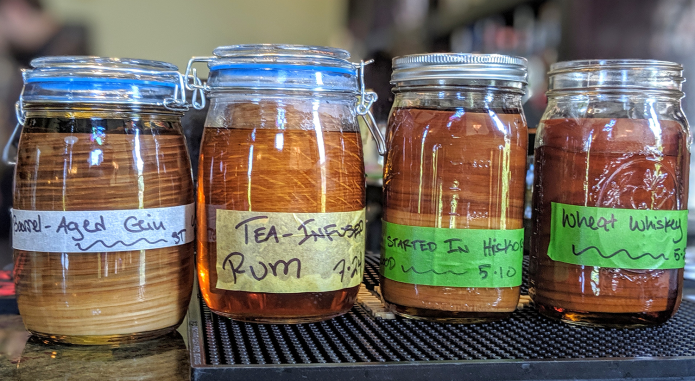 Four jars of different types of rum are sitting on a bar.