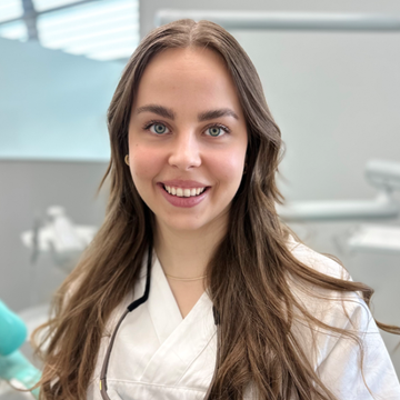 Tannlege Christian med briller og skjegg, iført blå skjorte og medisinsk maske, smiler til kameraet.