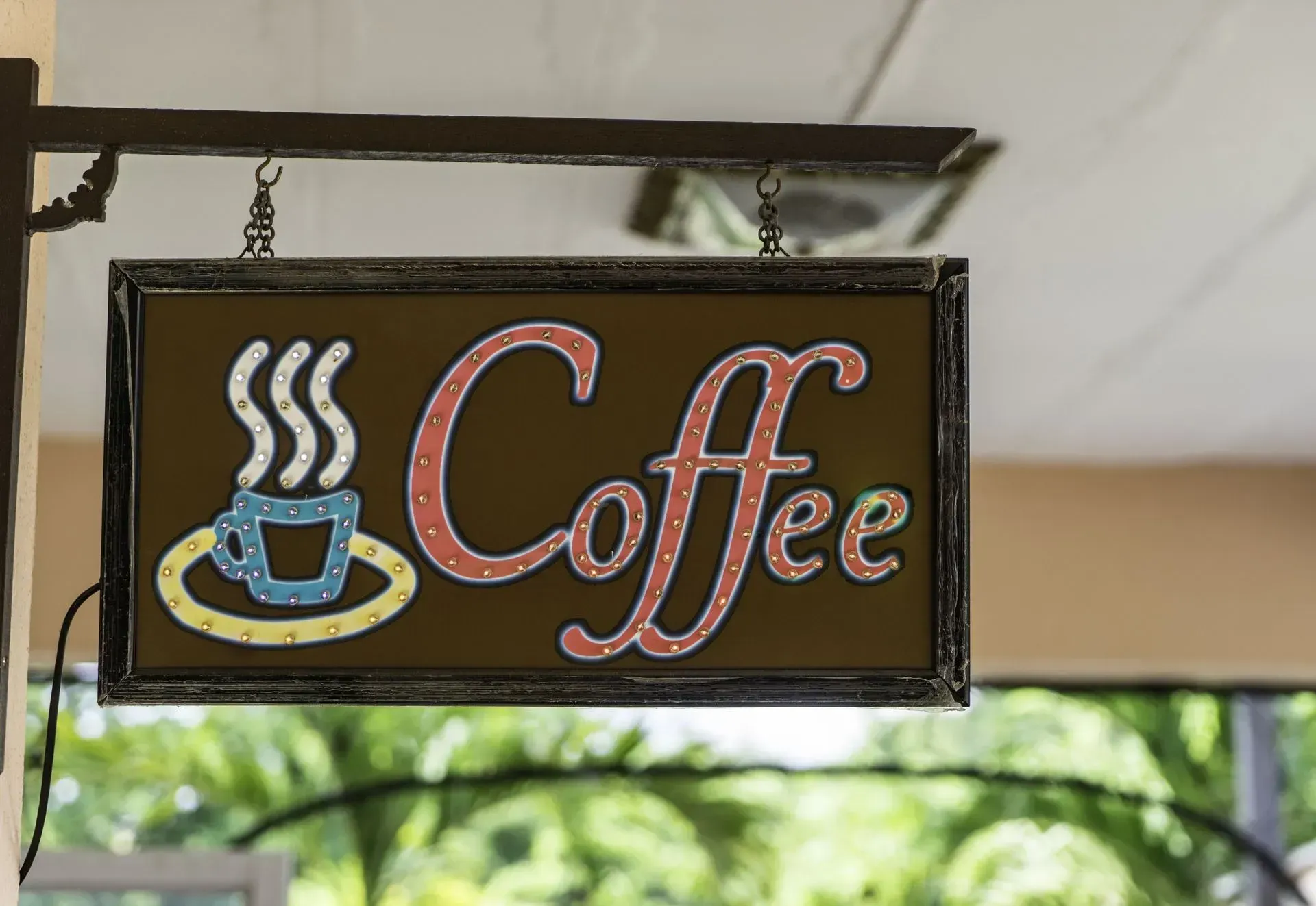 Hanging black sign with steaming coffee cup and pink “Coffee” lettering
