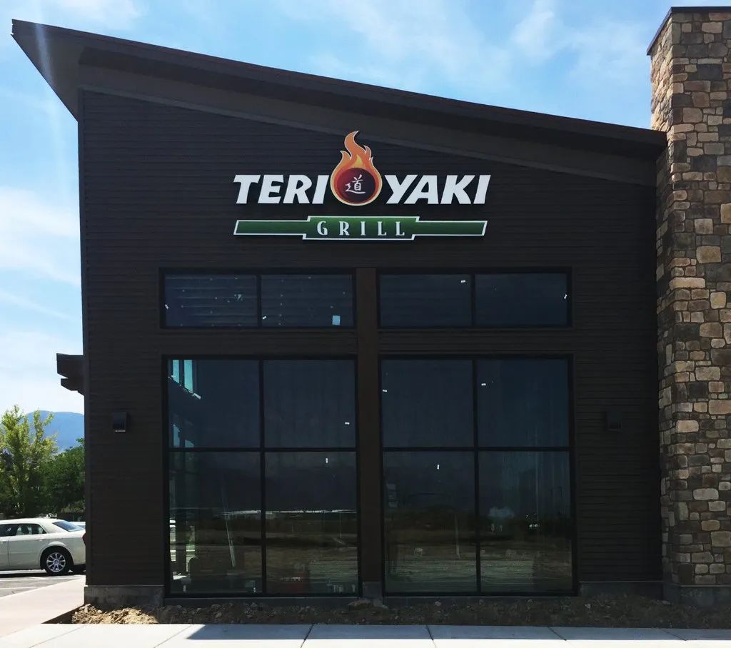 Exterior of Teriyaki Grill restaurant with dark facade and stone accents