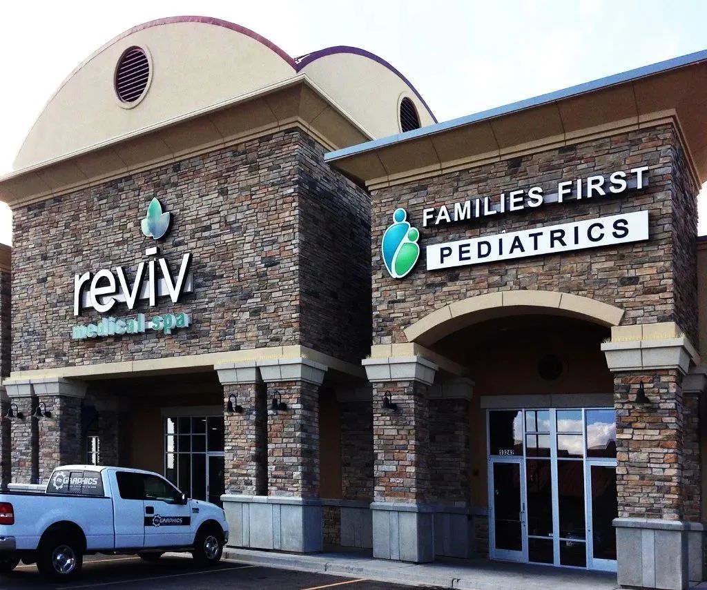 Reviv and Families First Pediatrics storefront in a stone shopping center with a parked pickup truck